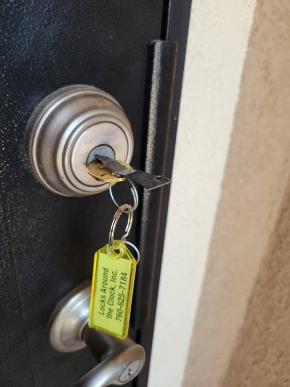 Freshly rekeyed residential deadbolt with the Locks Around the Clock branded service tag attached